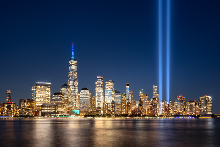 Night view of Lower Manhattan skyline, illuminated skyscrapers and projection into sky of twin beams of light. September 11 Tribute in Light commemoration above the Financial District, New York City