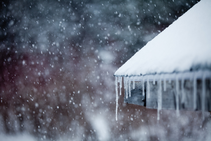 Icicles forming on the edge of a roof during a winter storm