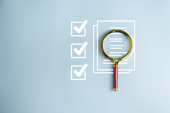 Magnifying glass over a fundraising review checklist and document, illustrating charity fundraising oversight and donor trust.