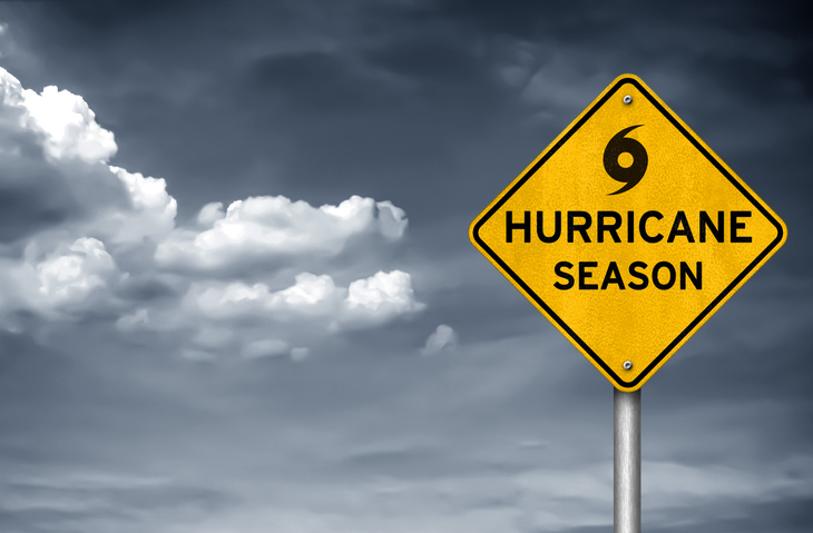 Yellow hurricane season warning sign in front of dark storm clouds