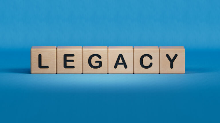 Wooden cubes spelling “legacy” on a blue background.