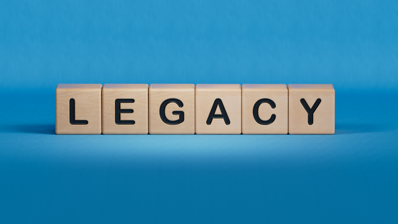 Wooden cubes spelling “legacy” on a blue background.